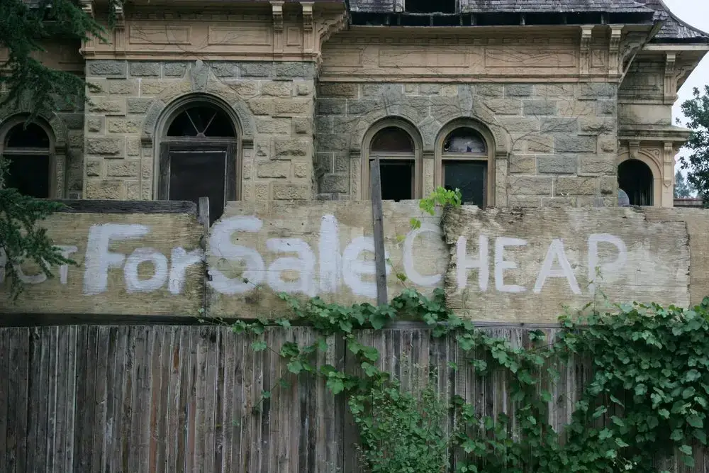 Fixer-upper house with "For Sale CHEAP" sign, illustrating renovation investment opportunities in Ottawa.